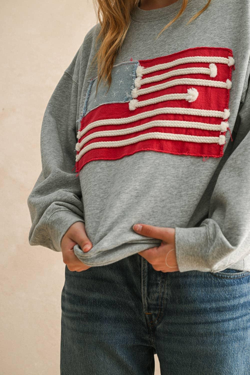 Miou Muse grey sweatshirt featuring a distressed American flag patch detail.