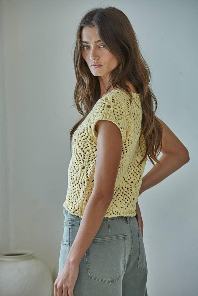 Yellow crochet top with open knit pattern paired with green jeans
