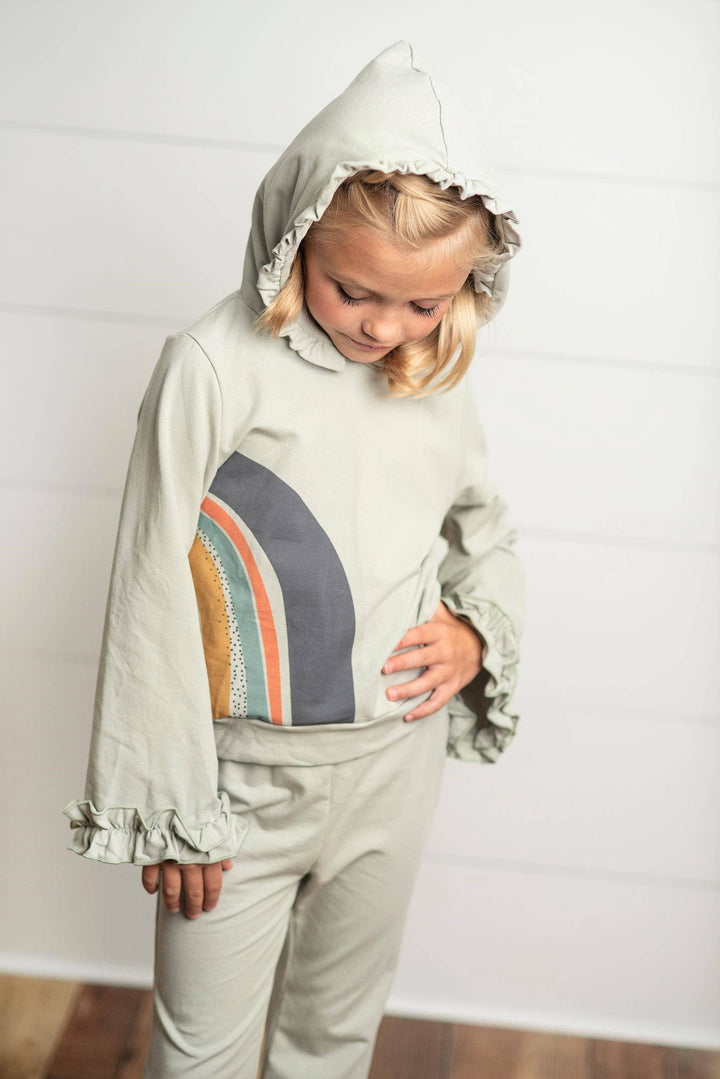 Girl wearing a gray sage Oopsie Daisy rainbow hooded sweatsuit lounge set