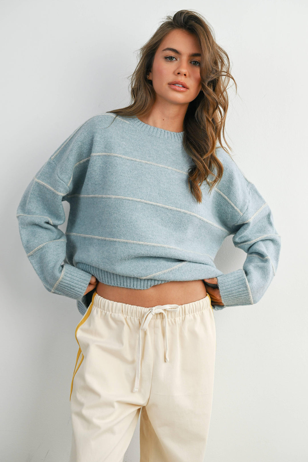 Woman in light blue striped sweater and cream joggers, coastal casual style