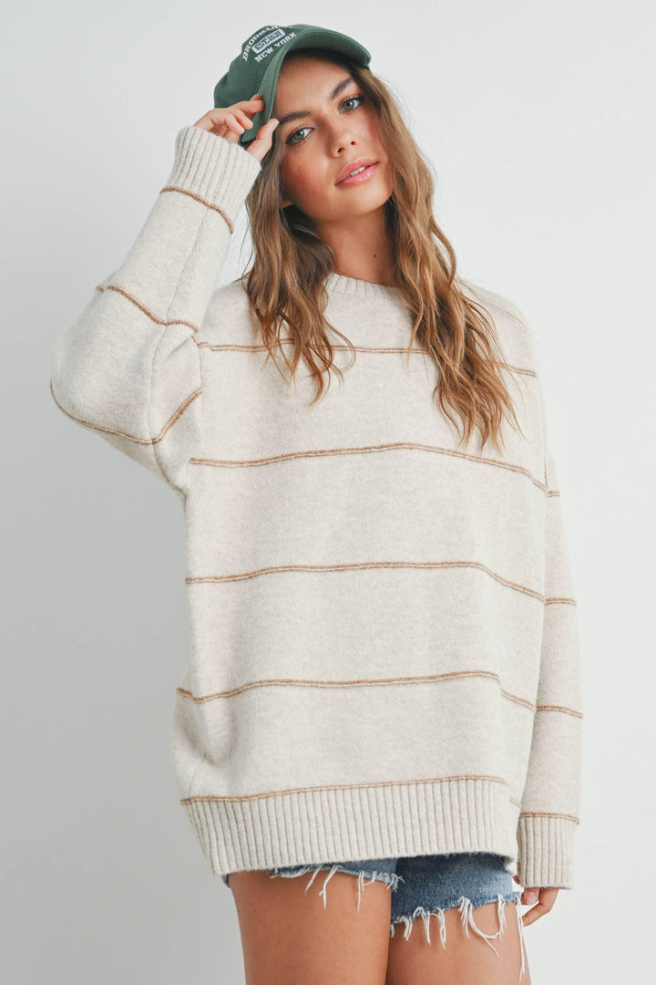 Woman in cozy cream striped sweater with green cap and denim shorts, casual fall outfit