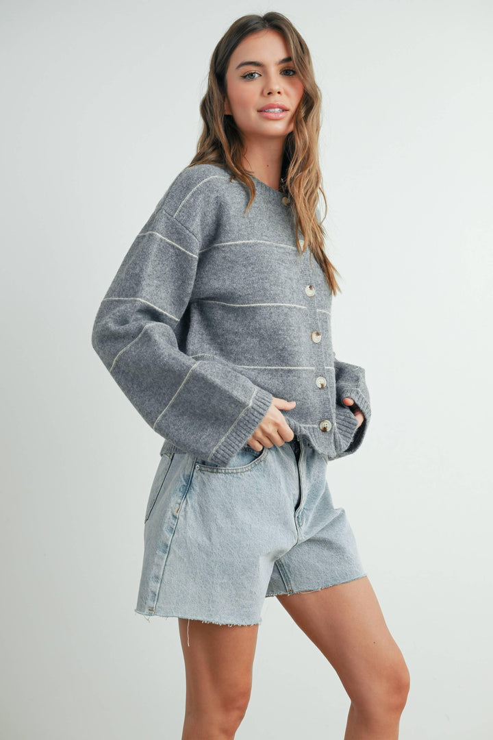 Woman in cozy gray button-up sweater and light wash denim shorts, coastal casual style