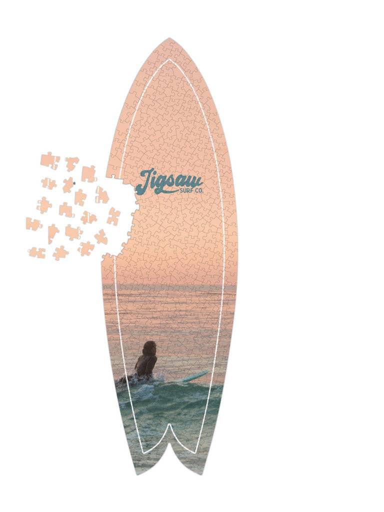 Surfboard-shaped jigsaw puzzle with ocean sunset scene and surfer