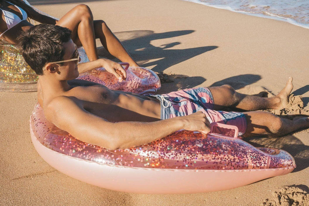 Man relaxing on glittery pink pool float at beach, perfect for coastal summer adventures and PNW weekends