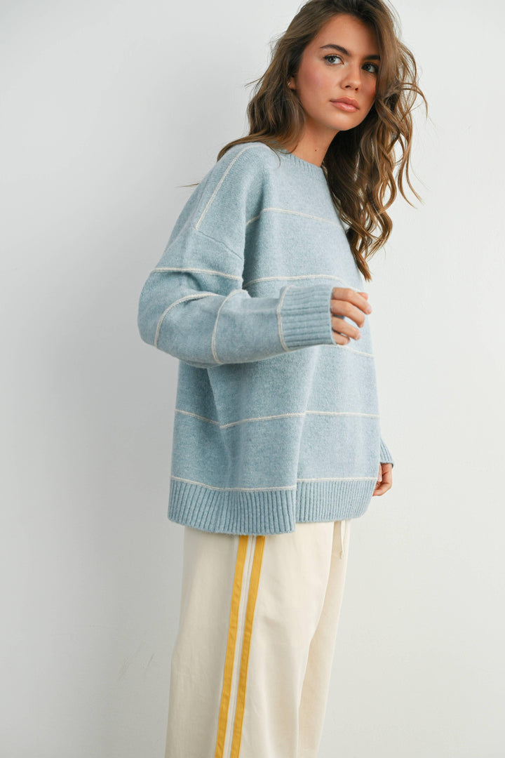 Light blue striped knit sweater with cream accents, paired with cream pants featuring yellow side stripes, ideal for coastal PNW style.