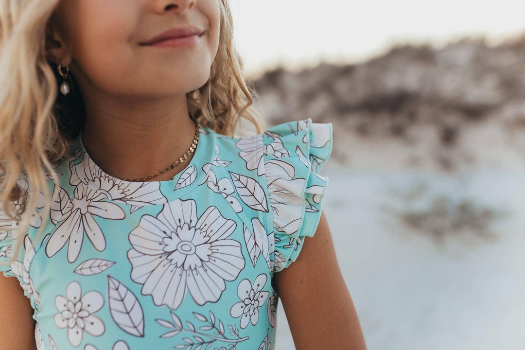 Girl in mint floral dress with ruffle sleeves at the beach, coastal style outfit