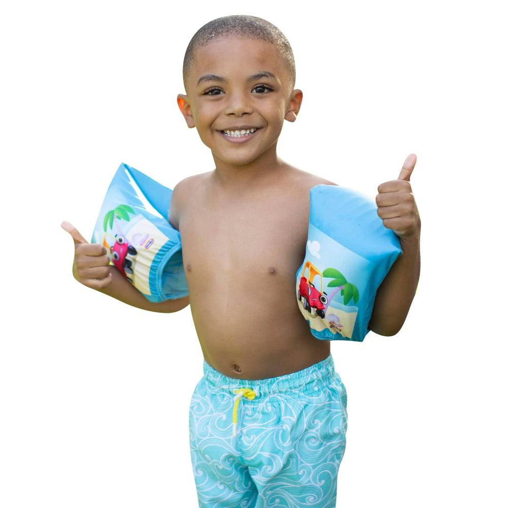 Child wearing blue swim floaties with car and palm tree designs, giving thumbs up