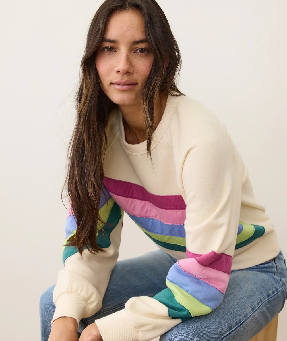 Woman in cream sweatshirt with colorful rainbow stripes, coastal style outfit