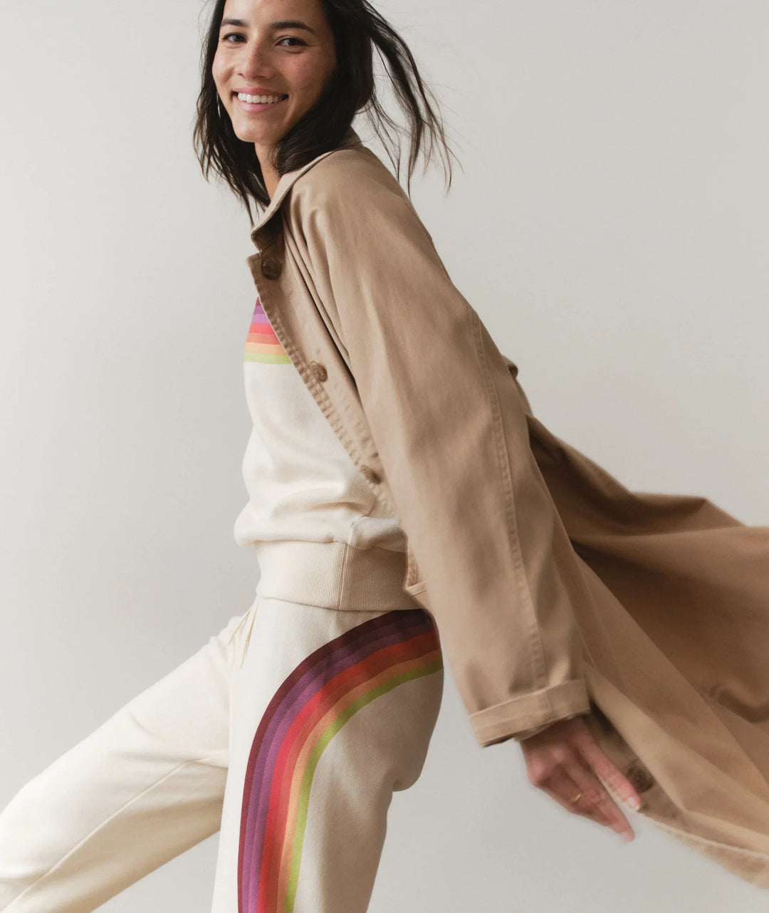 Woman in beige jacket and rainbow stripe sweatpants, coastal PNW style
