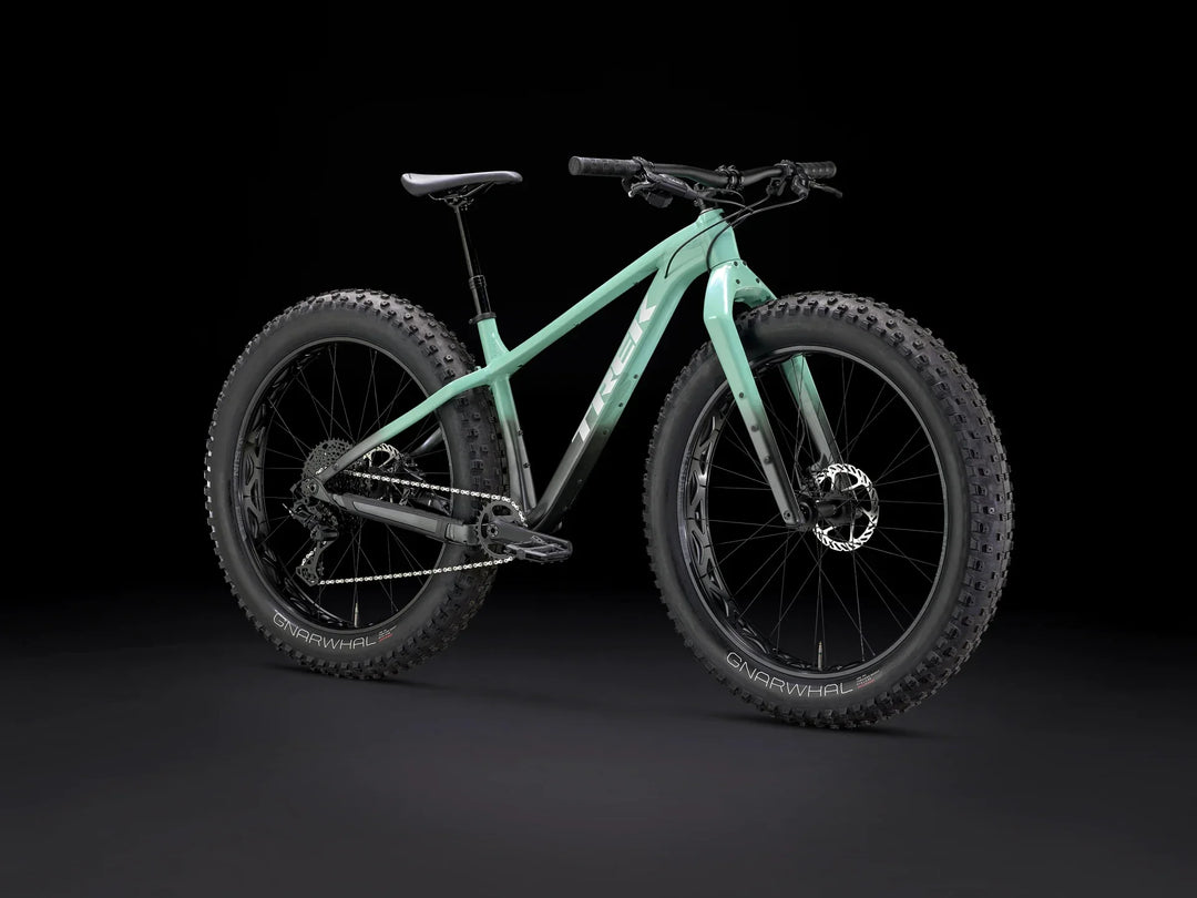 Mint green fat-tire mountain bike with wide GNARWHAL tires, sleek frame, and disc brakes on black background