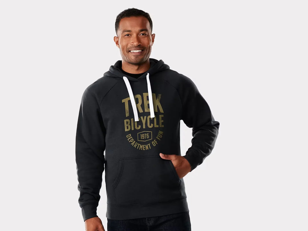 Man wearing black Trek Bicycle hoodie with gold vintage logo, white drawstrings, and front pocket