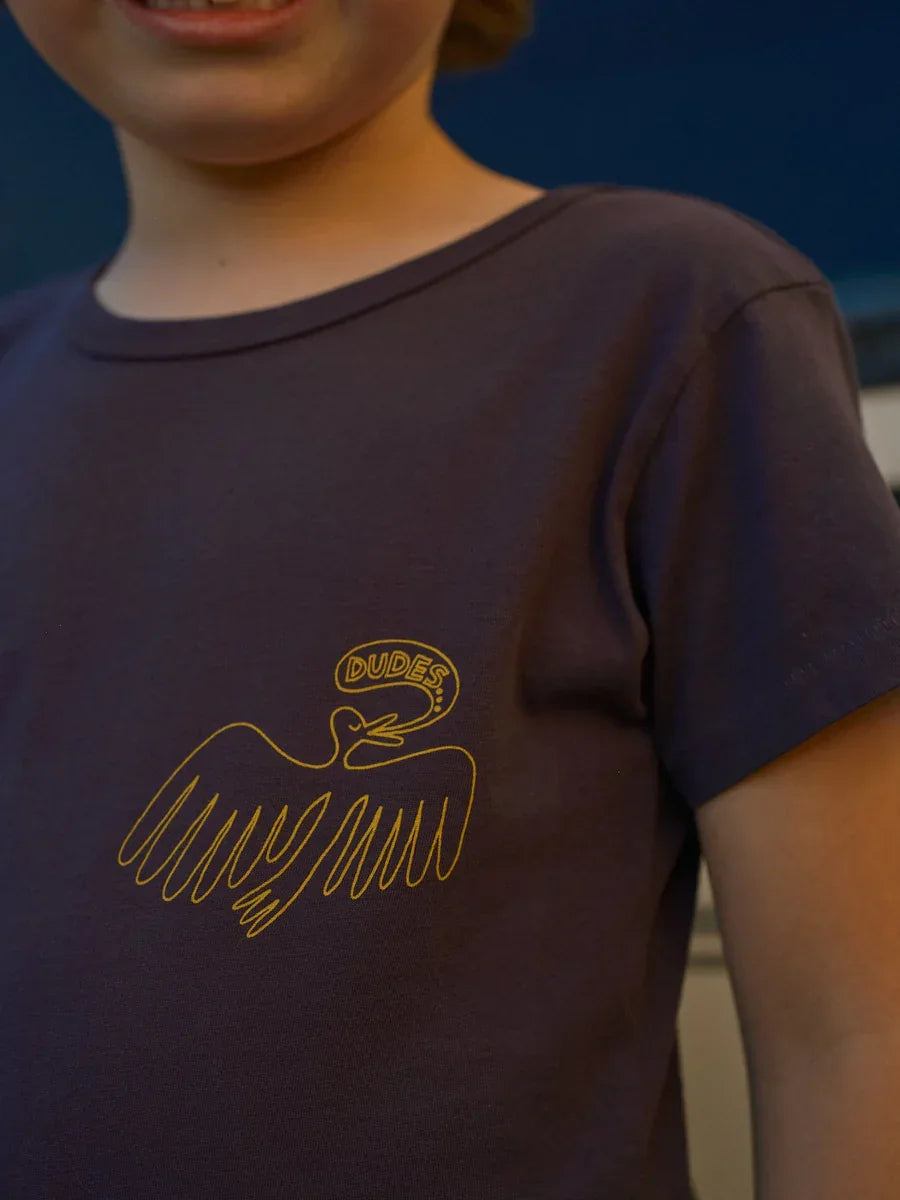 Kid wearing dark tee with yellow 'Dudes' bird graphic, casual kids apparel
