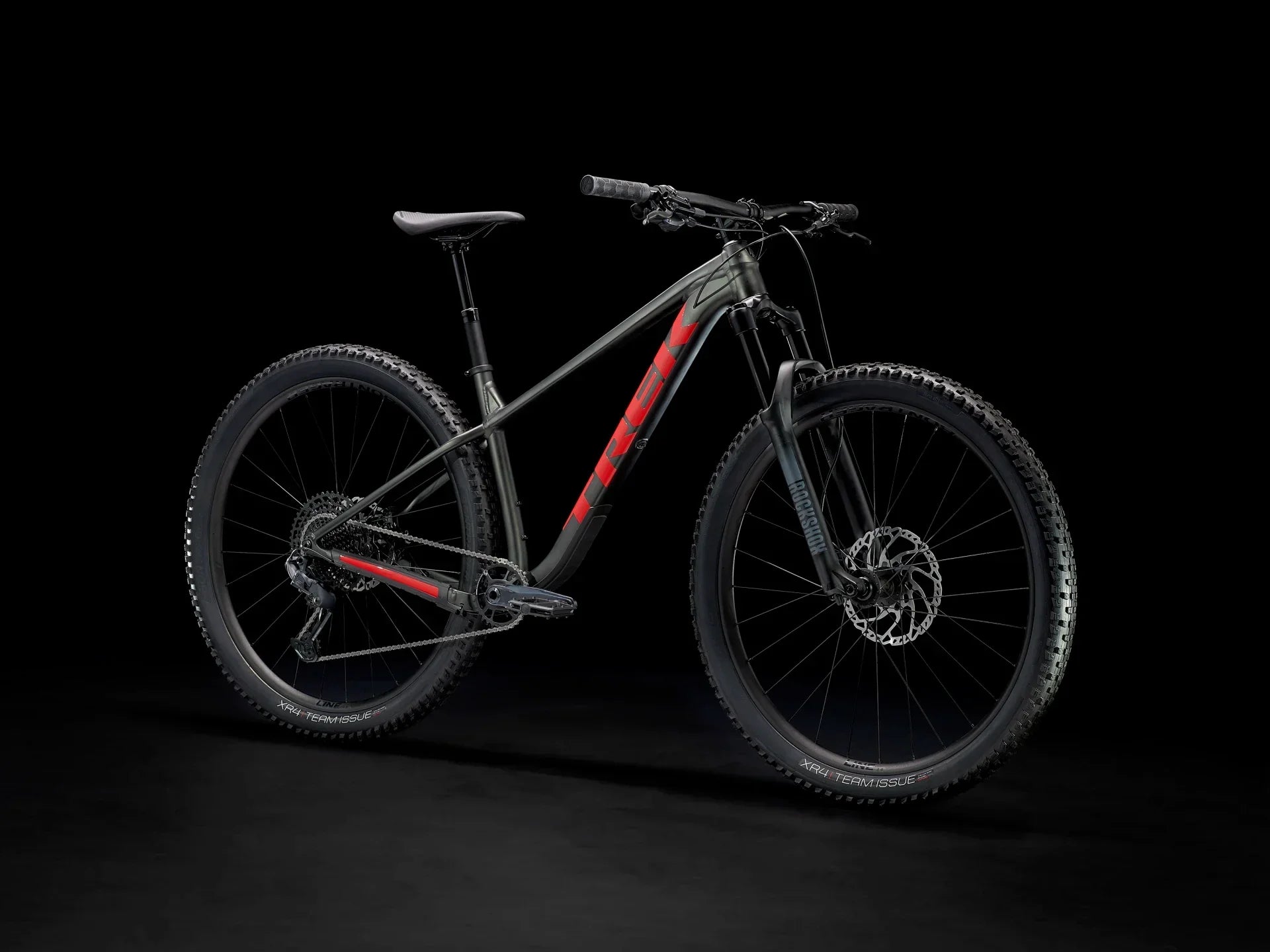 Black and red mountain bike with rugged tires and disc brakes on dark background