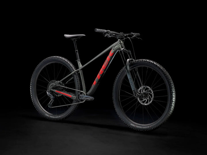 Black and red mountain bike with rugged tires and disc brakes on dark background