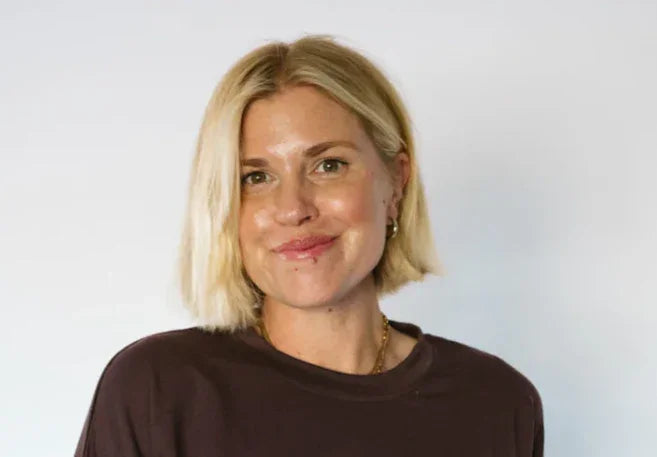 Blonde woman in brown shirt smiling against white background