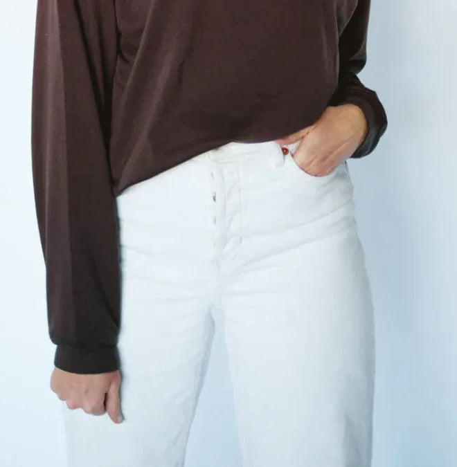 White high-waisted jeans paired with brown long-sleeve top, coastal outdoor style