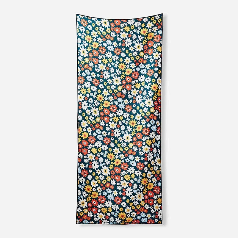 Colorful floral beach towel with vibrant daisies on dark teal background, perfect for coastal adventures and outdoor lifestyle.