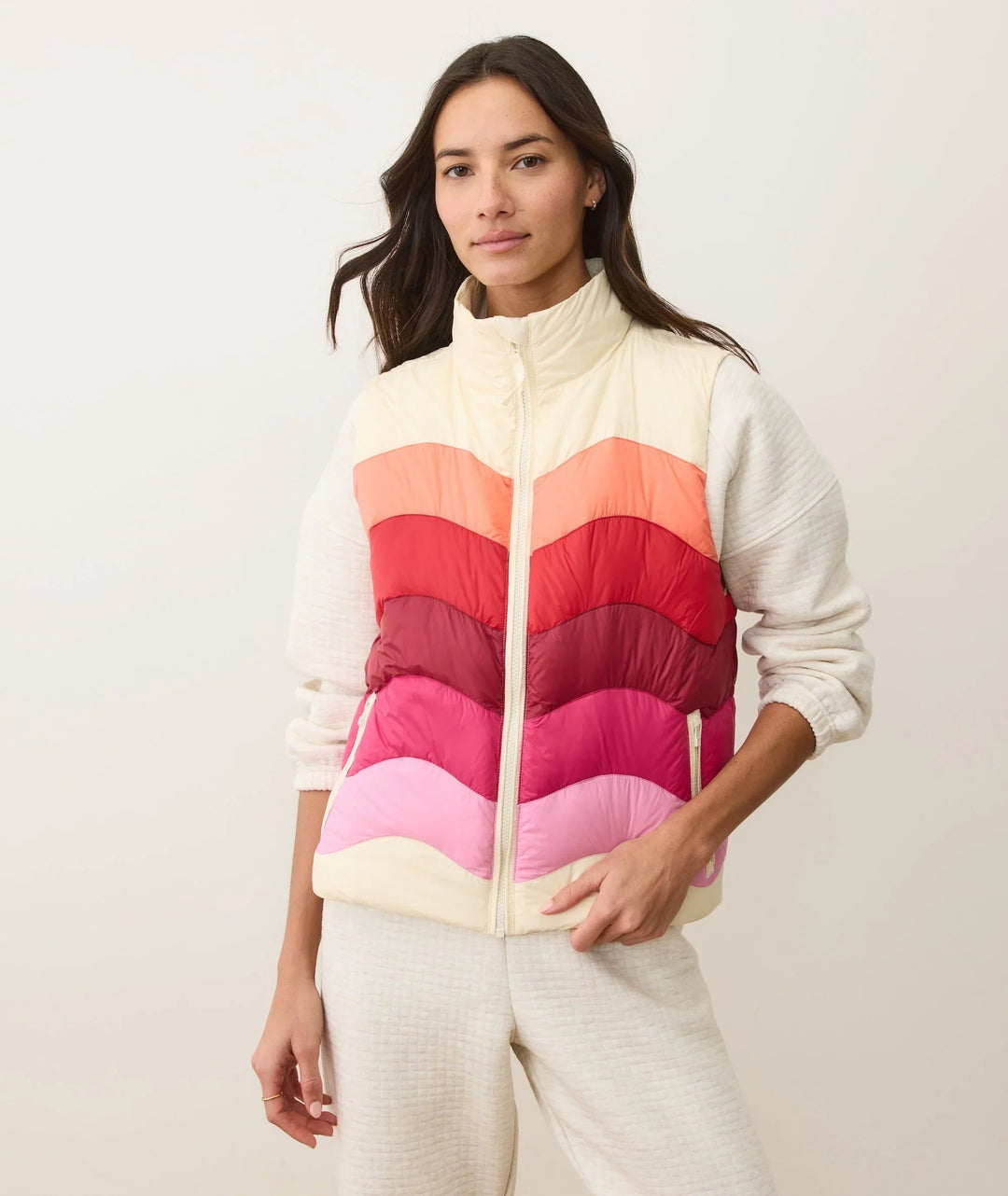 Woman wearing colorful striped puffer vest over cozy cream sweater, perfect for PNW outdoor adventures