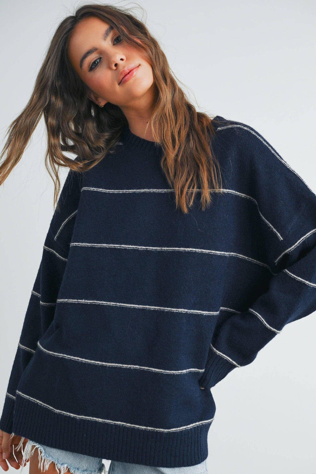Navy blue striped oversized sweater with white horizontal lines, worn by woman with wavy hair