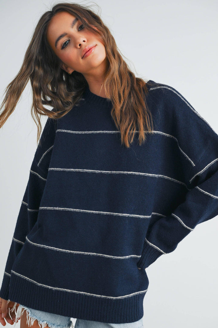 Navy blue striped oversized sweater with white horizontal lines, worn by woman with wavy hair
