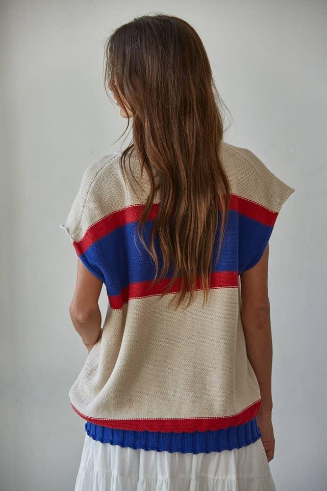 Back view of woman wearing striped knit top with red and blue bands, coastal style outfit