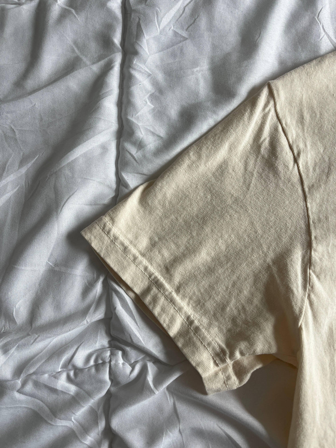 Cream cotton t-shirt sleeve detail on white fabric, coastal style everyday wear