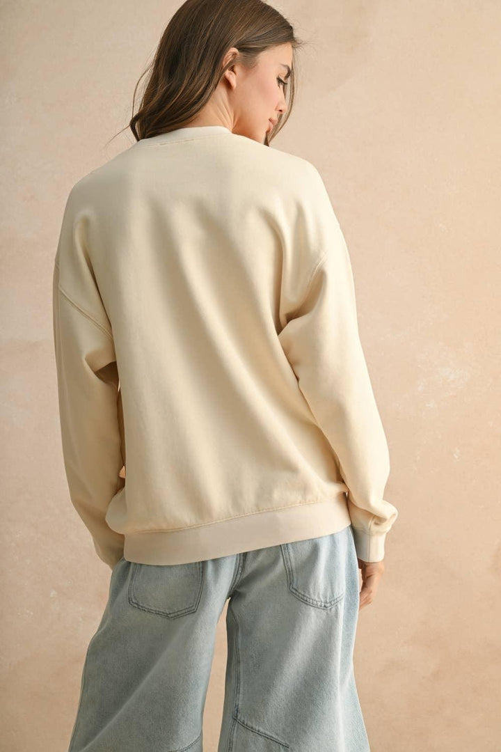 Back view of a woman wearing a cream MIOU MUSE sweatshirt and light wash denim jeans.