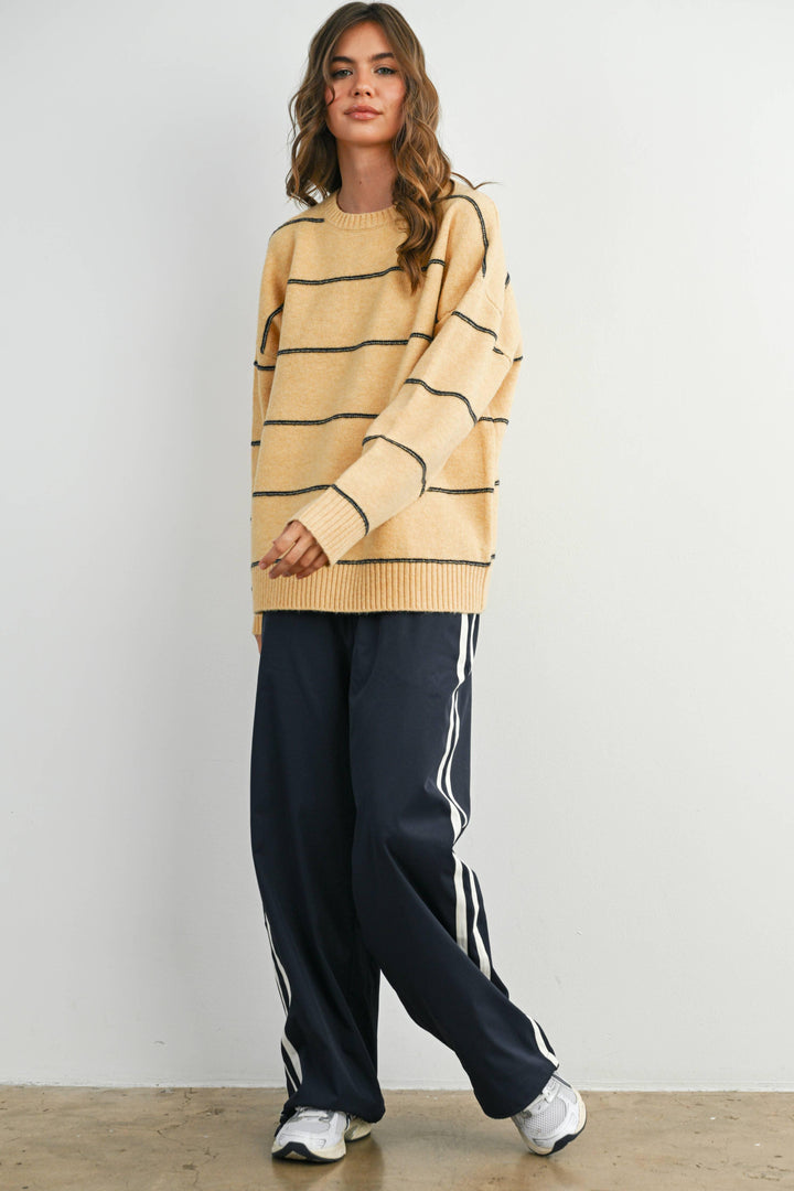 Woman in cozy yellow striped sweater, navy track pants, and white sneakers for casual PNW style