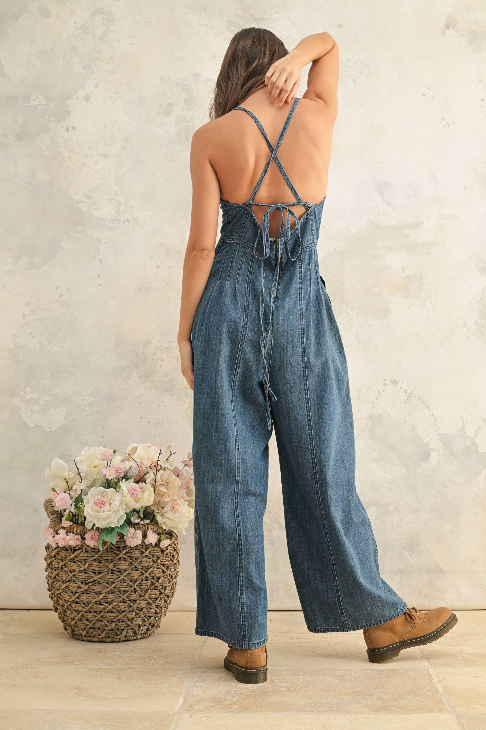 Denim jumpsuit with crisscross back and wide legs, paired with brown boots and floral basket