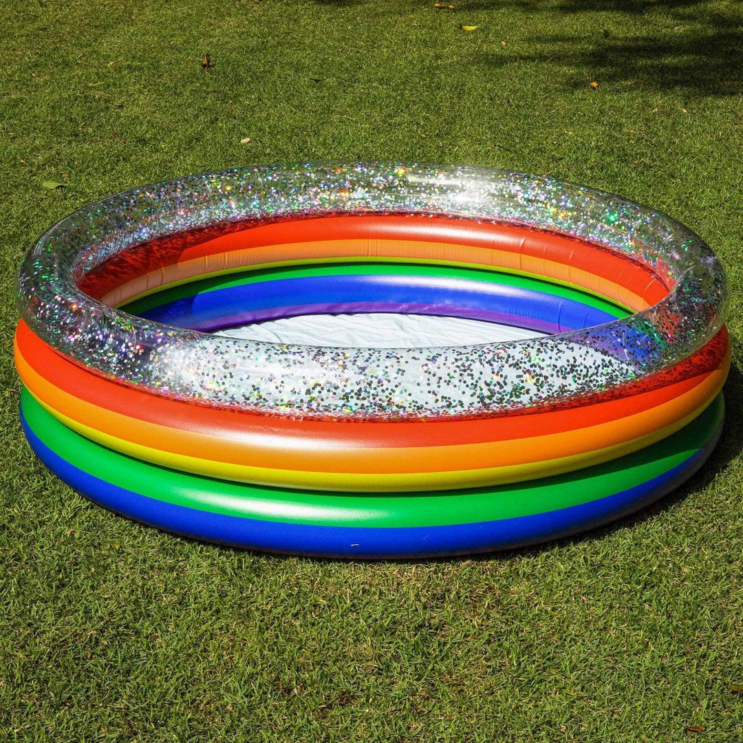 Rainbow glitter inflatable pool on grass, perfect for backyard fun and outdoor adventures.