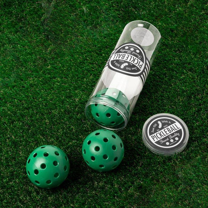 Green pickleball balls in clear tube on grass, outdoor game gear for PNW adventures