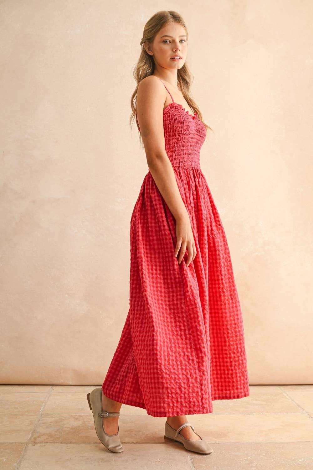 Woman in red gingham maxi dress with smocked bodice and thin straps, paired with neutral flats