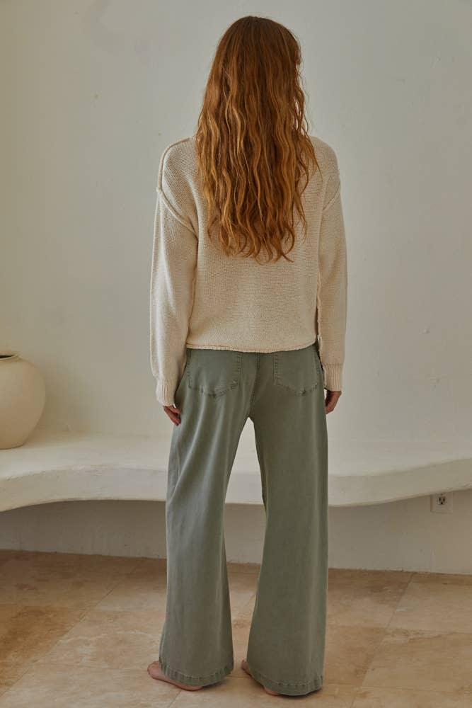 Woman in cozy cream sweater and olive wide-leg pants, back view, coastal style