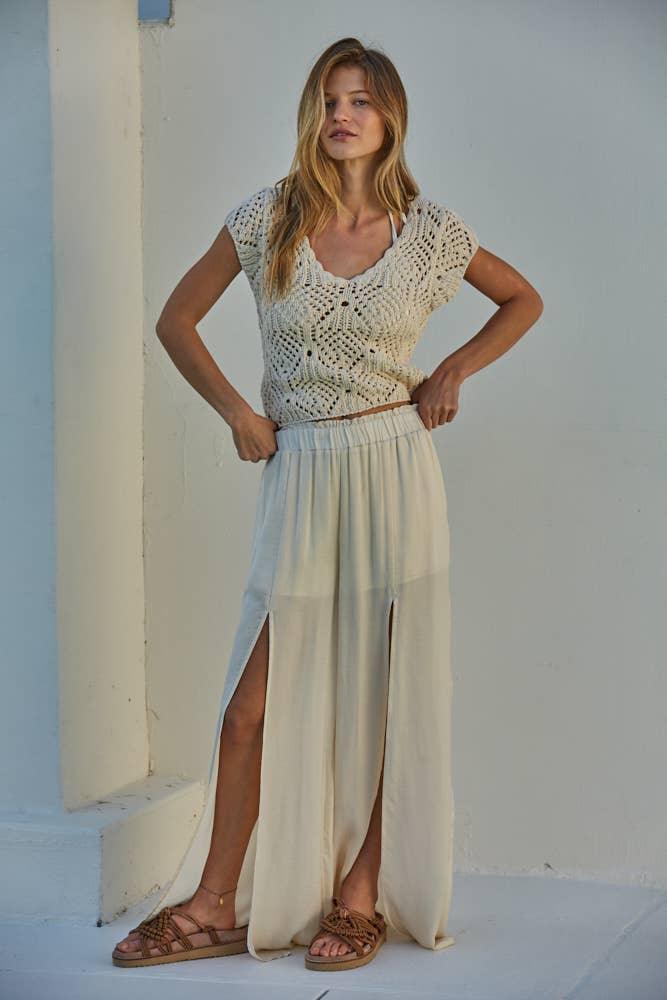 Woman in cream crochet top and wide-leg slit pants, boho summer outfit
