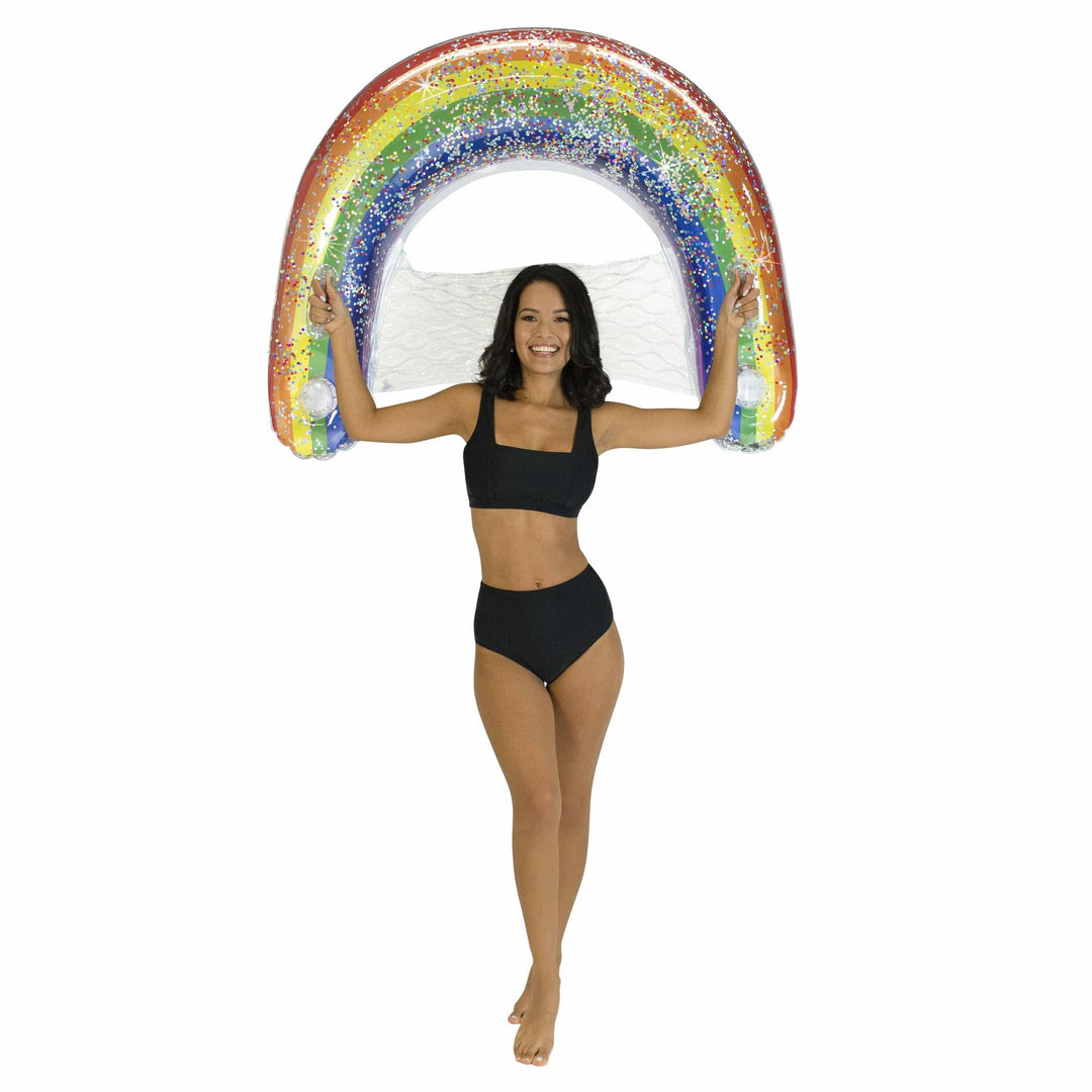 Woman holding glittery rainbow inflatable pool float, perfect for beach days and summer adventures