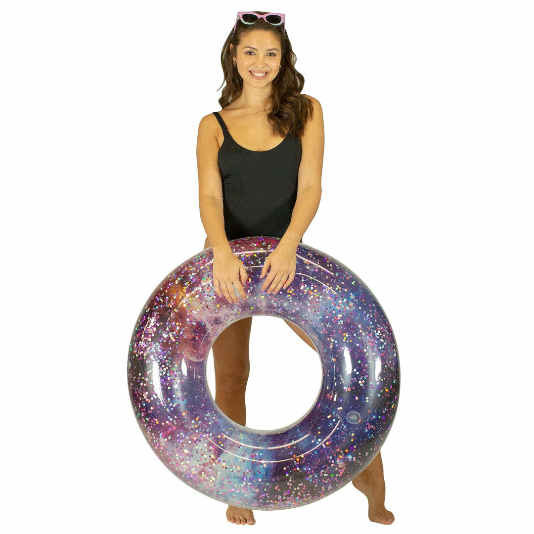 Woman holding galaxy glitter inflatable pool float for beach days and summer adventures