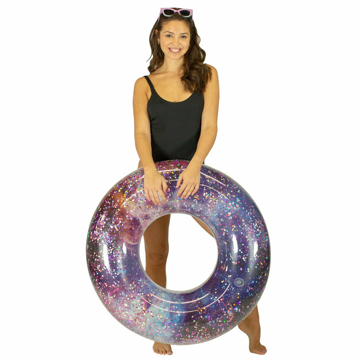 Woman holding galaxy glitter inflatable pool float for beach days and summer adventures