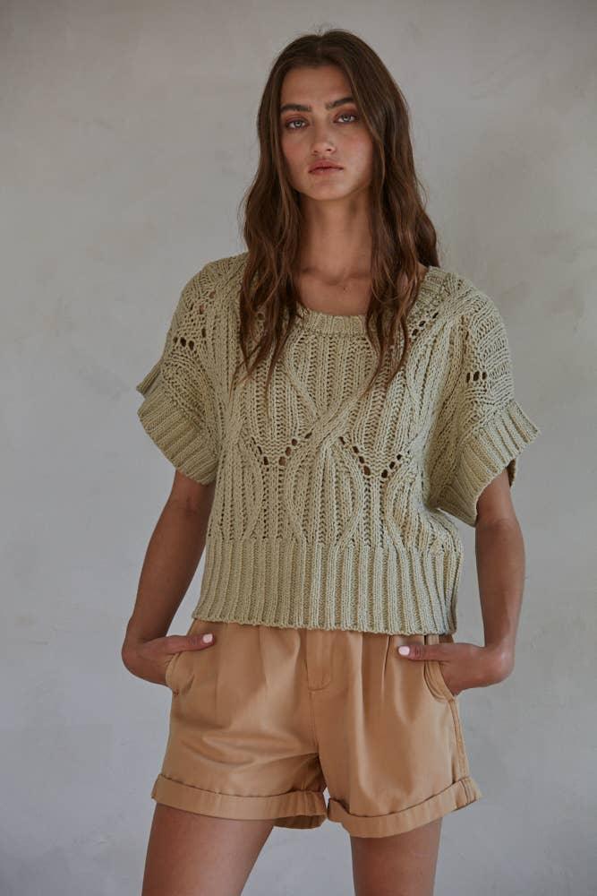 Woman wearing olive knit crop top with short sleeves and tan shorts, casual summer outfit