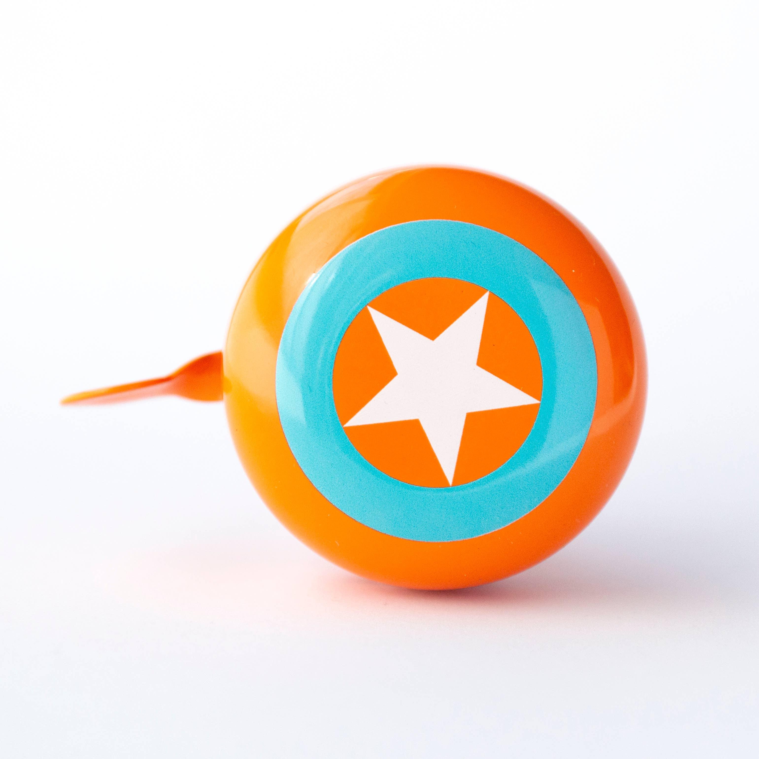 Orange bike bell with white star and blue ring, perfect for coastal adventures and trail rides.