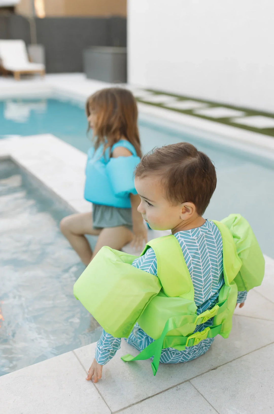Kids in bright swim vests by poolside, enjoying water safety gear for summer fun