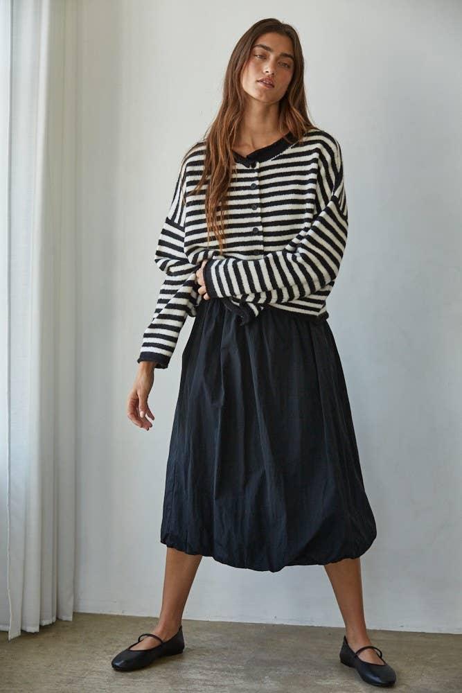 Woman in black and white striped cardigan with navy midi skirt, coastal style outfit