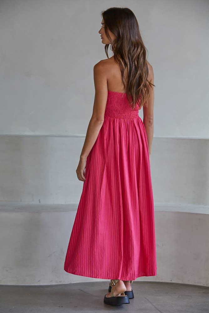 Woman in vibrant pink strapless pleated maxi dress, perfect for coastal weekends and beach days.