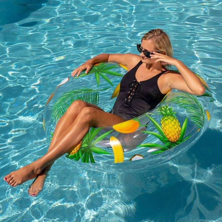 Woman relaxing on tropical fruit inflatable pool float in sunny swimming pool