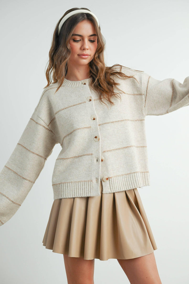 Cream button-front cardigan with ribbed trim, paired with pleated skirt and headband for cozy coastal style