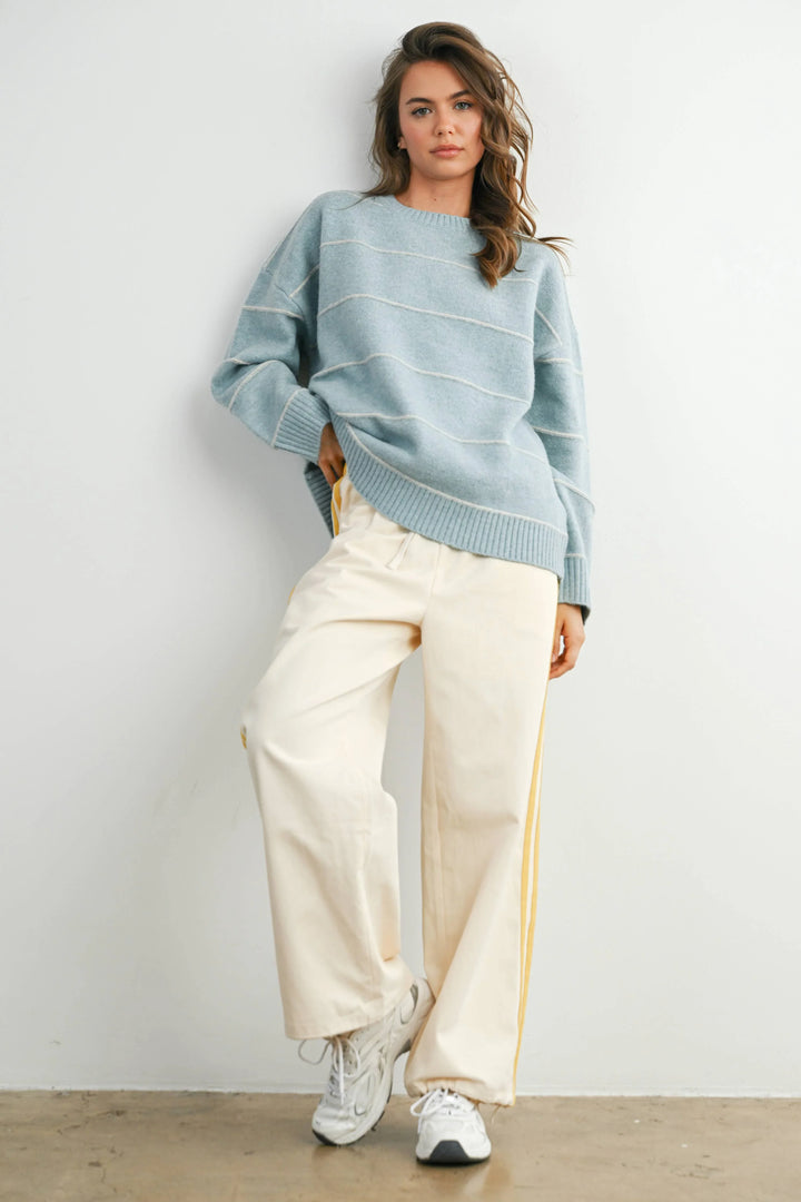 Woman in light blue striped sweater and cream wide-leg pants with yellow side stripes, styled for coastal PNW adventures.