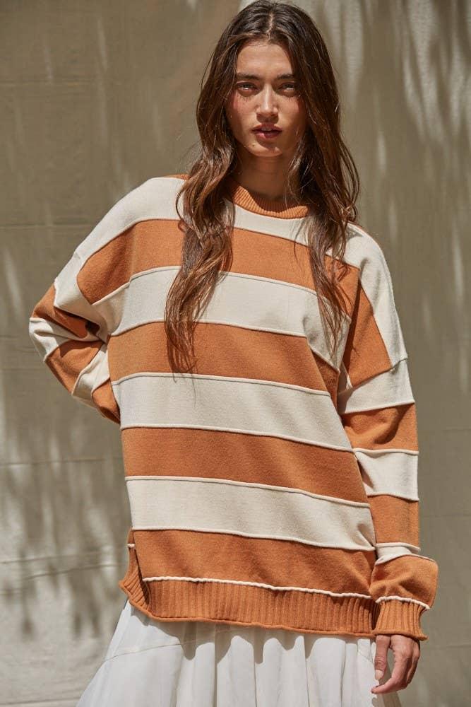 Woman wearing cozy orange and cream striped sweater, perfect for PNW coastal style and outdoor adventures.