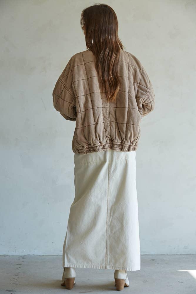 Tan quilted bomber jacket with grid pattern, paired with cream maxi skirt and block heels