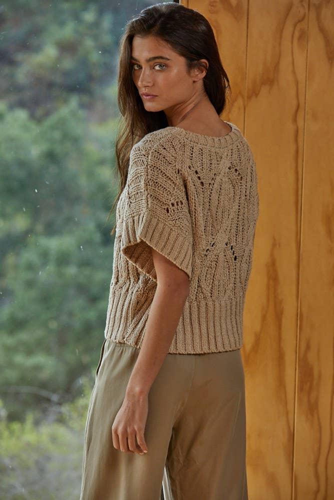 Woman in cozy beige knit sweater with short sleeves, styled for PNW coastal adventures and outdoor lifestyle.