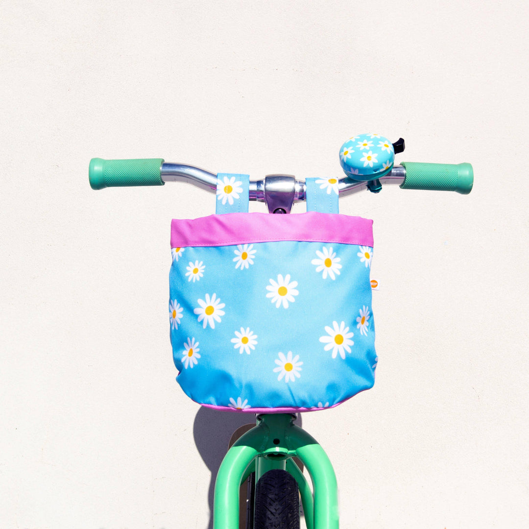 Kids bike with daisy print basket, mint green handlebars, and matching bell for outdoor adventures.
