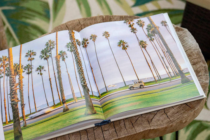Open photo book showing palm trees, coastal road, and vintage SUV — perfect for beach days and outdoor adventures.